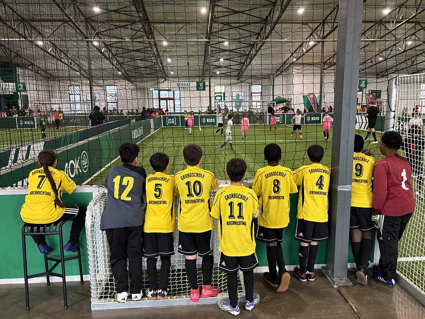 Eine Fußballmanschaft in gelben Trikots schaut einem anderes Spiel zu