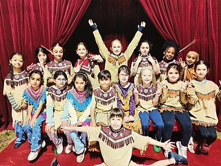 Viele Kinder stehen vor einem roten Vorhang